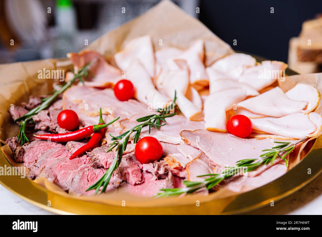 Eine köstliche Auswahl an dünnen Fleischscheiben, einschließlich Rind- und Schweinewürsten, Schinken und roter Paprika mit Rosmarin. Begleitet von frischer kirschtomate Stockfoto