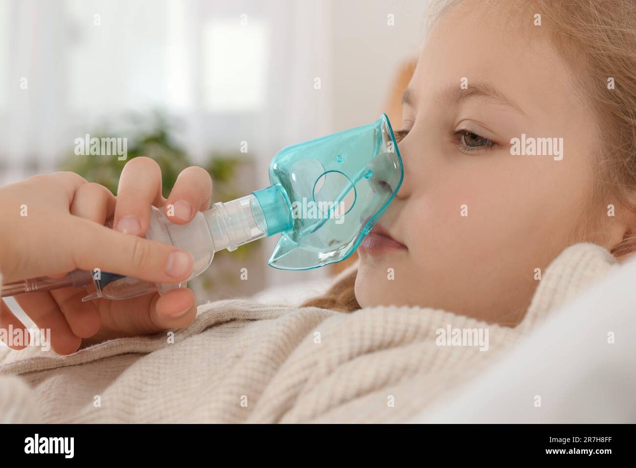 Kleines Mädchen, das Vernebler zur Inhalation im Schlafzimmer benutzt, Nahaufnahme Stockfoto