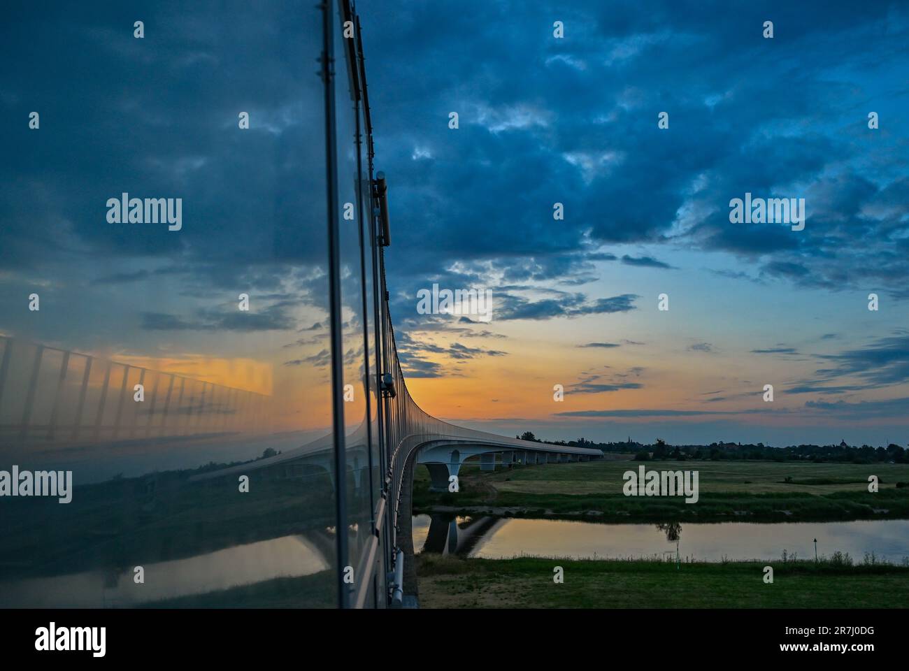 16. Juni 2023, Brandenburg, Mühlberg: Blick am frühen Morgen bei Sonnenaufgang vom Sächsischen Ufer bis zur Elbbrücke der Stadt Mühlberg im Bundesland Brandenburg. Hier in Mühlberg bildet die Elbe die Staatsgrenze zwischen Sachsen und Brandenburg. Foto: Patrick Pleul/dpa Stockfoto