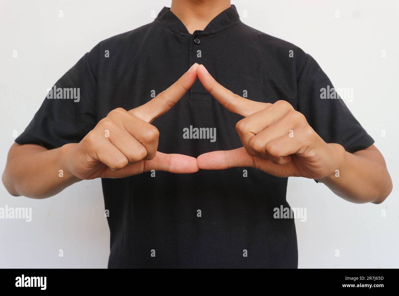 Der Mann mit dem schwarzen Hemd hob seine Hand, um die Dreiecksform zu zeigen. Stockfoto
