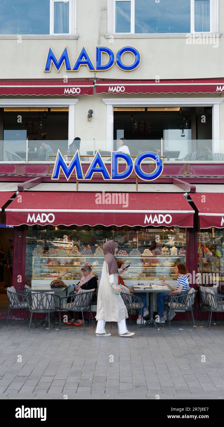 Eine Frau, die einen Hijab pflegt, läuft am Mado Coffee Shop in Karakoy, Istanbul, Türkei vorbei Stockfoto