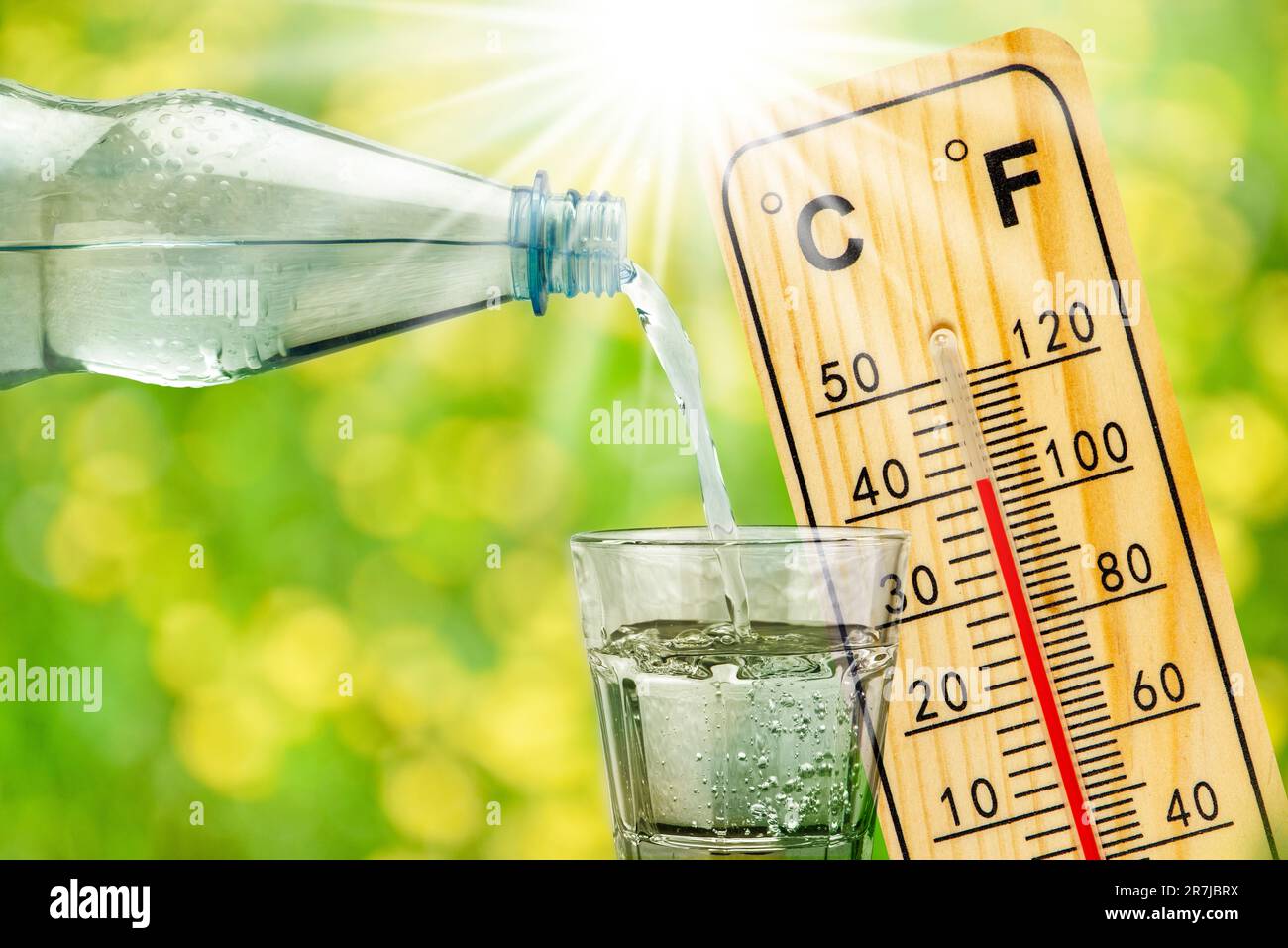 Thermometer zeigt hohe Temperaturen in der Sommerhitze und Flasche mit Wasser mit Trinkglas an Stockfoto