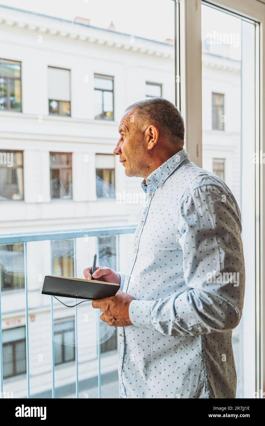 Porträt-Mann mittleren Alters, der Notizen in Notizbuch macht Stockfoto