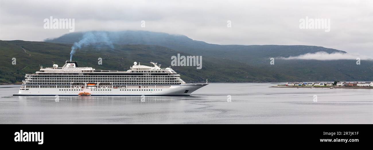 Negative Auswirkungen des Kreuzfahrttourismus: Das riesige Kreuzfahrtschiff ankert in Loch Broom neben den kleinen Häusern von Ullapool, Ross und Cromarty, Schottland, Großbritannien Stockfoto