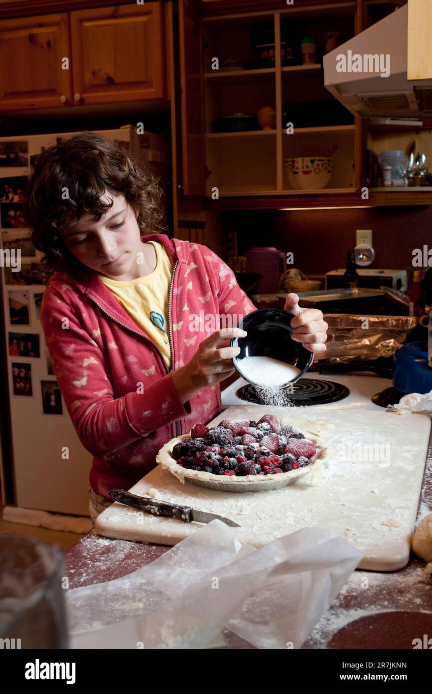 Ein 13-jähriges Mädchen schüttet Zucker auf einen hausgemachten Beerkuchen in einem Landhaus in Ontario, Kanada. Stockfoto