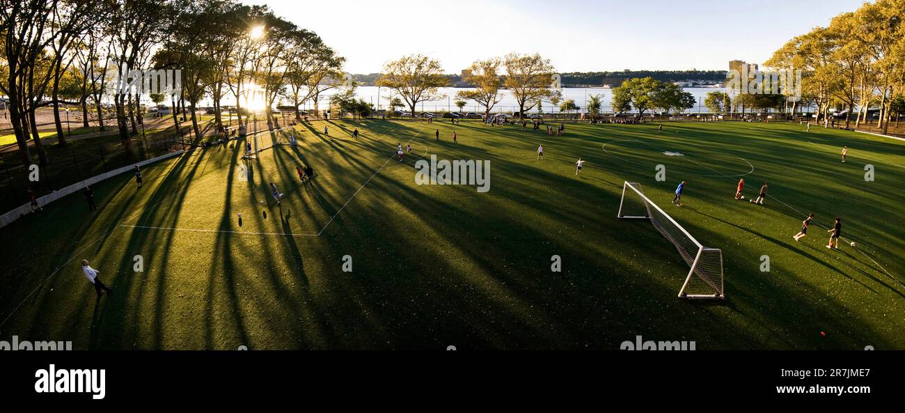 Die untergehende Sonne wirft lange Schatten über ein Fußballfeld im Riverside Park an der Upper West Side in Manhattan. Stockfoto