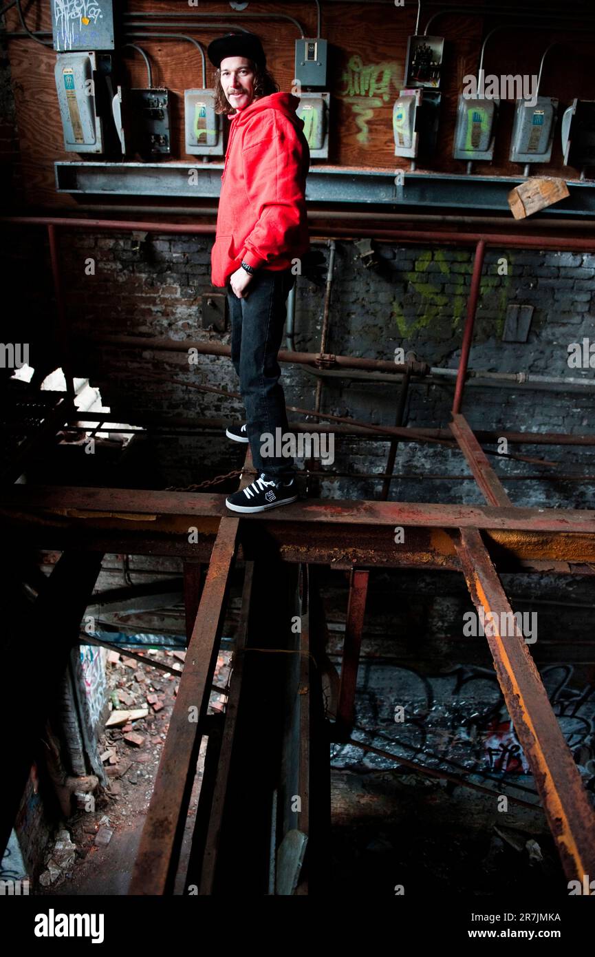Ein Mann steht auf I-Balken in einem verlassenen Industriegebäude. Stockfoto