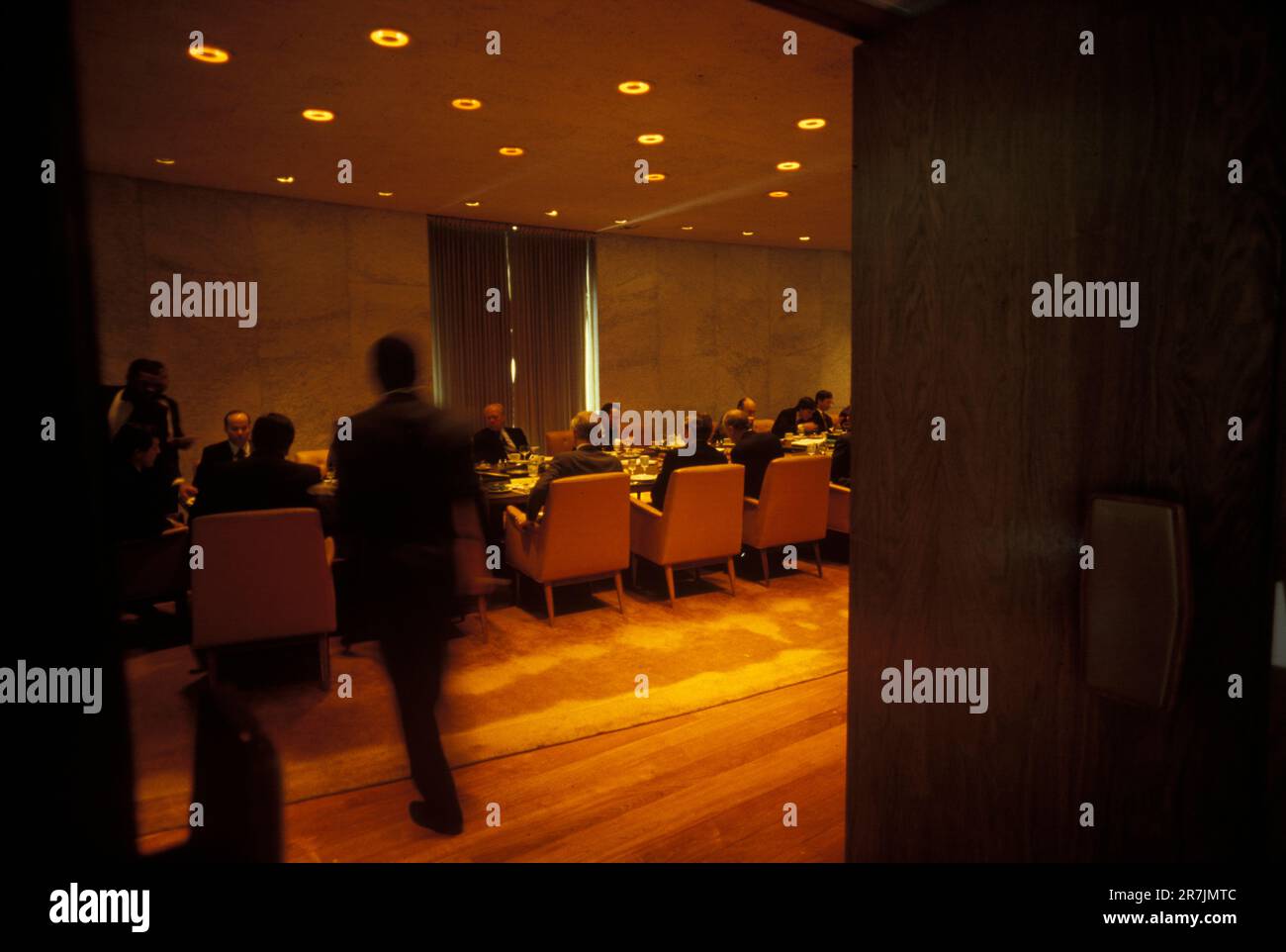 Der ehemalige Vorsitzende eines großen Finanzunternehmens nimmt an einem formellen Abendessen in einem schwach beleuchteten Bankettsaal Teil. Stockfoto