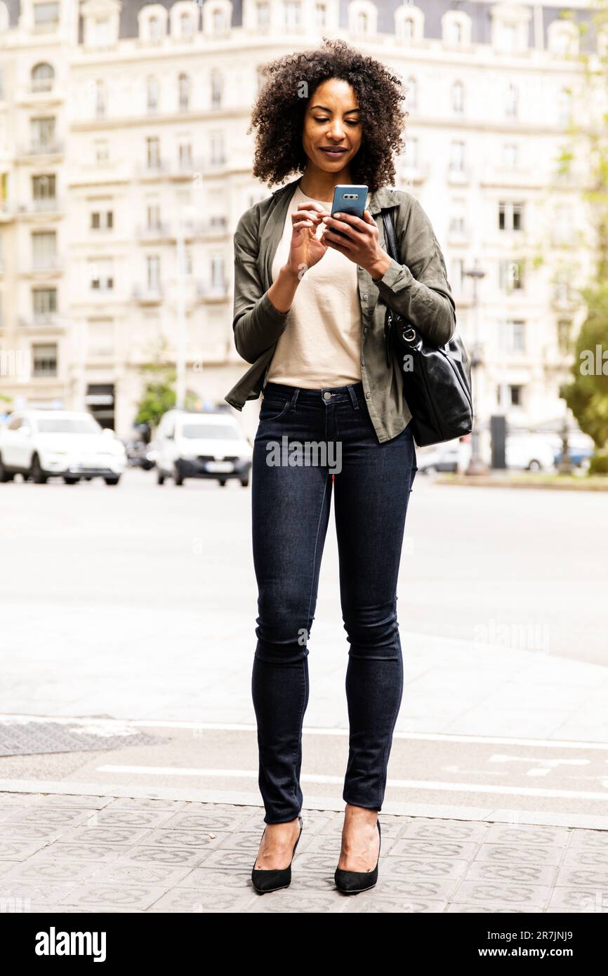 Schöne entspannte Frau, die mit seinem Handy auf der Straße SMS schreibt. Stockfoto
