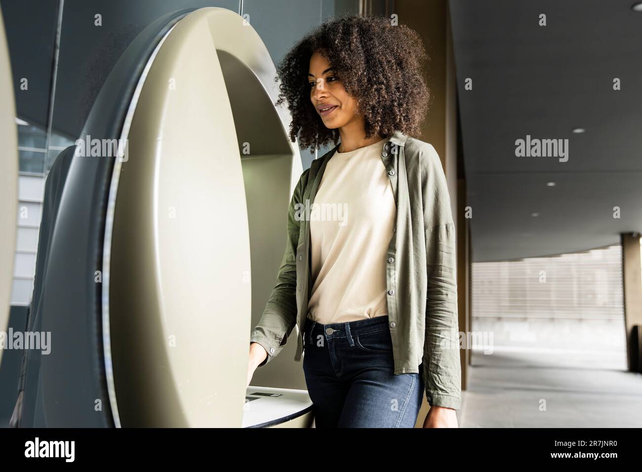 Eine sorglose Frau, die einen Geldautomaten benutzt. Stockfoto