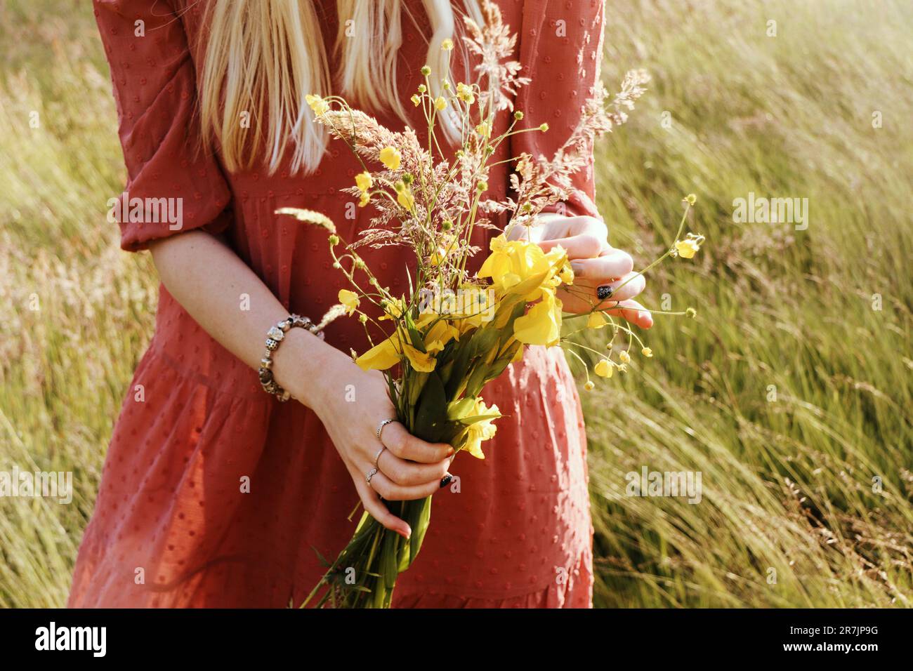 Strauß gelber Wildblumen in den Händen einer Frau Stockfoto