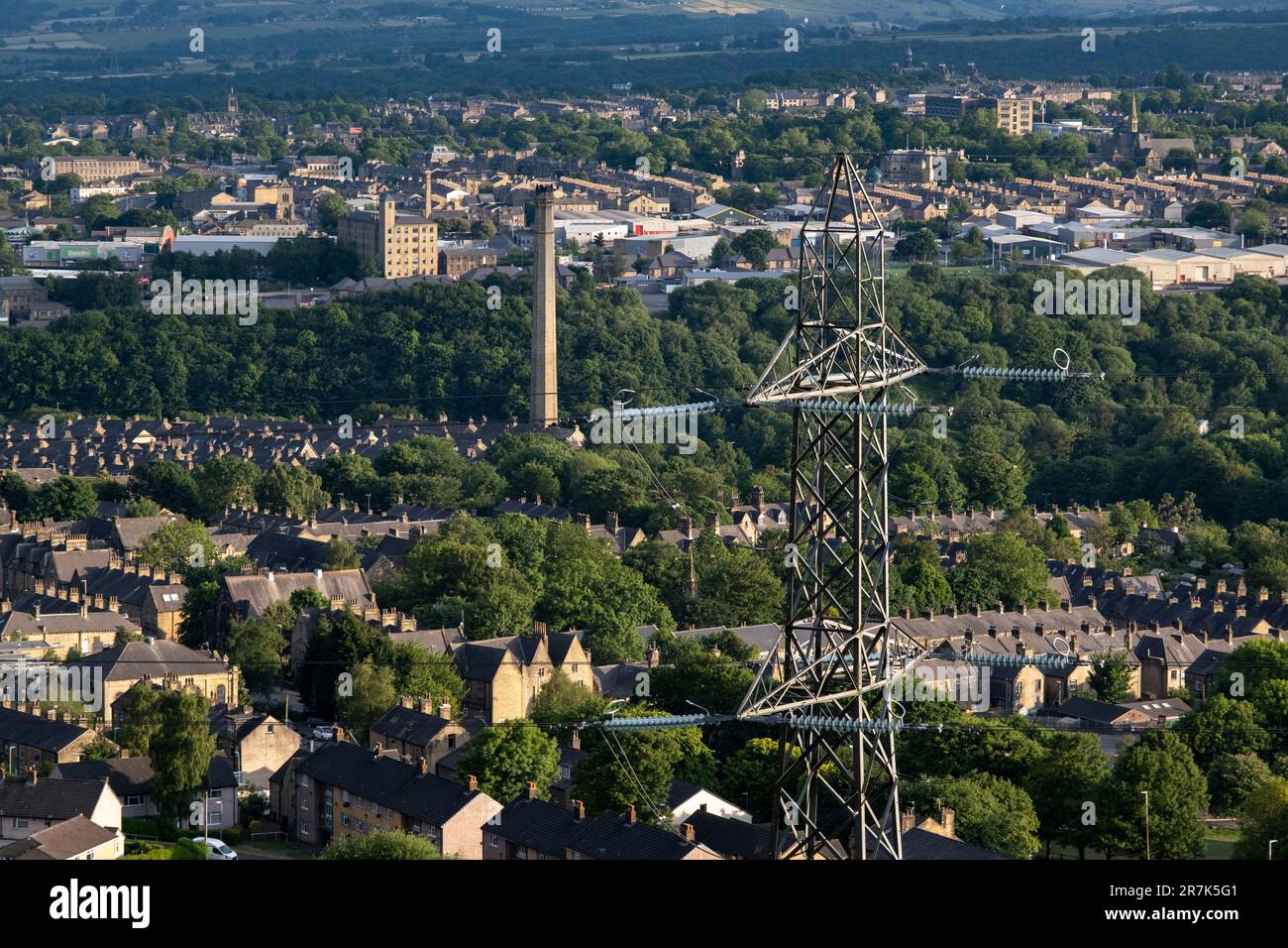 Am 8. Juni 2023 in Halifax, Großbritannien, blickten Strommasten auf Häuser außerhalb des Stadtzentrums. Halifax ist eine Stadt im Stadtteil Calderdale in West Yorkshire und war während der industriellen Revolution eine florierende Mühlenstadt. Diese Freileitungen ermöglichen die Übertragung und Verteilung elektrischer Energie über große Entfernungen hinweg, die Privathaushalte und Unternehmen in ganz Großbritannien antreiben. Stockfoto