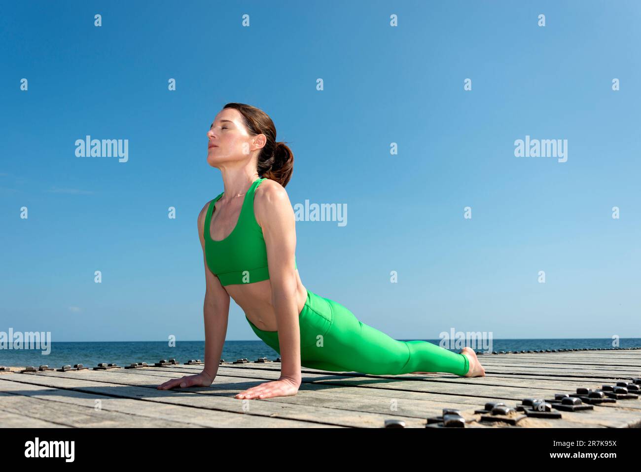 Fit Frau übt Yoga asana urdhva mukha svanasana - nach oben schauende Hundehaltung, draußen am Meer. Stockfoto
