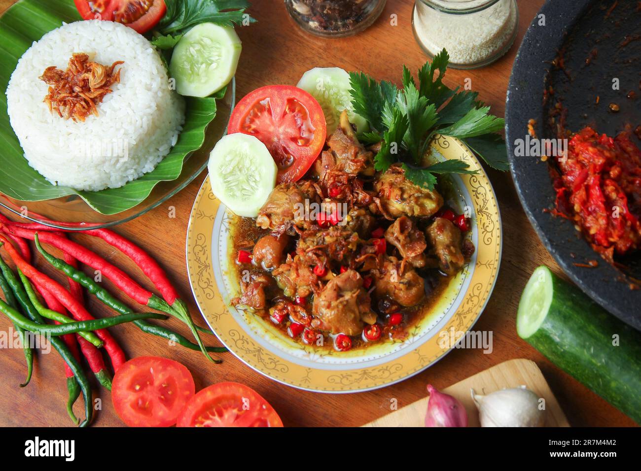 Indonesische Speisen in der Lebensmittelfotografie. Hühnchen rica-rica mit Tomaten, Gurken, Sellerie, Reis. Geschmortes scharfes Hähnchen mit Chili auf dem Tisch. Street Food kulinarisch Stockfoto