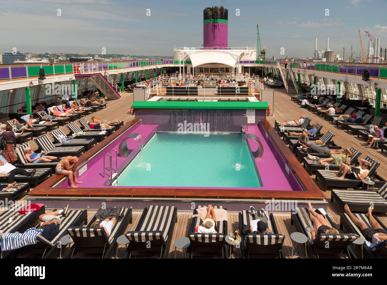 Le Harve Nordfrankreich. 2023. Kreuzfahrtpassagiere entspannen sich auf Liegen rund um den Swimmingpool an Deck, während das Schiff den Hafen verlässt. Stockfoto
