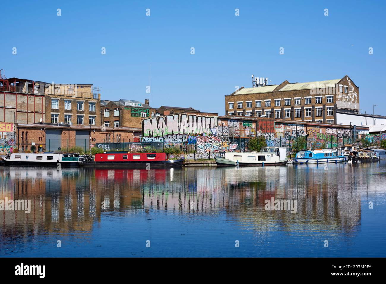 Schmalboote und Lagerhäuser entlang der River Lea Navigation in Hackney Wick, East London, Großbritannien, im Sommer Stockfoto