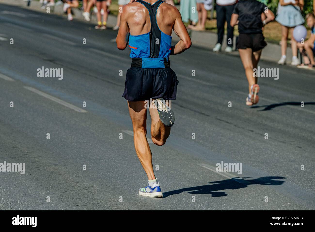 Rückansicht männlicher Läufer beim Laufen des City Marathons, heißer Wetterschweiß auf dem Rücken Stockfoto