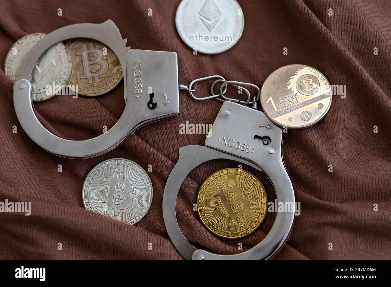 Golden Bitcoins Kryptowährung mit Handschellen auf Dollarscheinen. Konzept der digitalen Kriminalität, der Festnahme oder des Hacking. Handschellen Dollar und Bitcoins auf dem Tisch Stockfoto