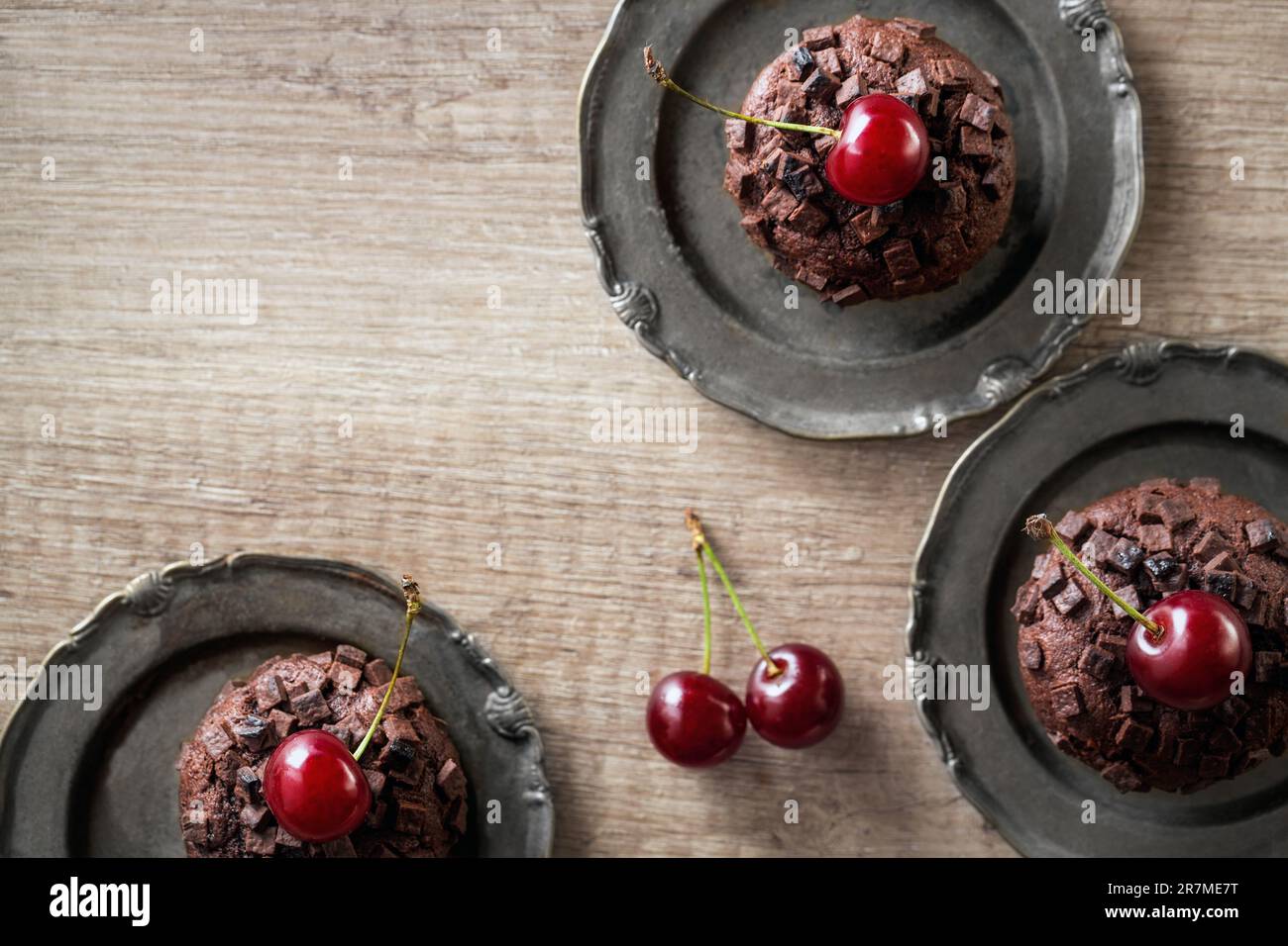 Schokoladen-Muffins im Hintergrund mit frischer Kirsche Stockfoto