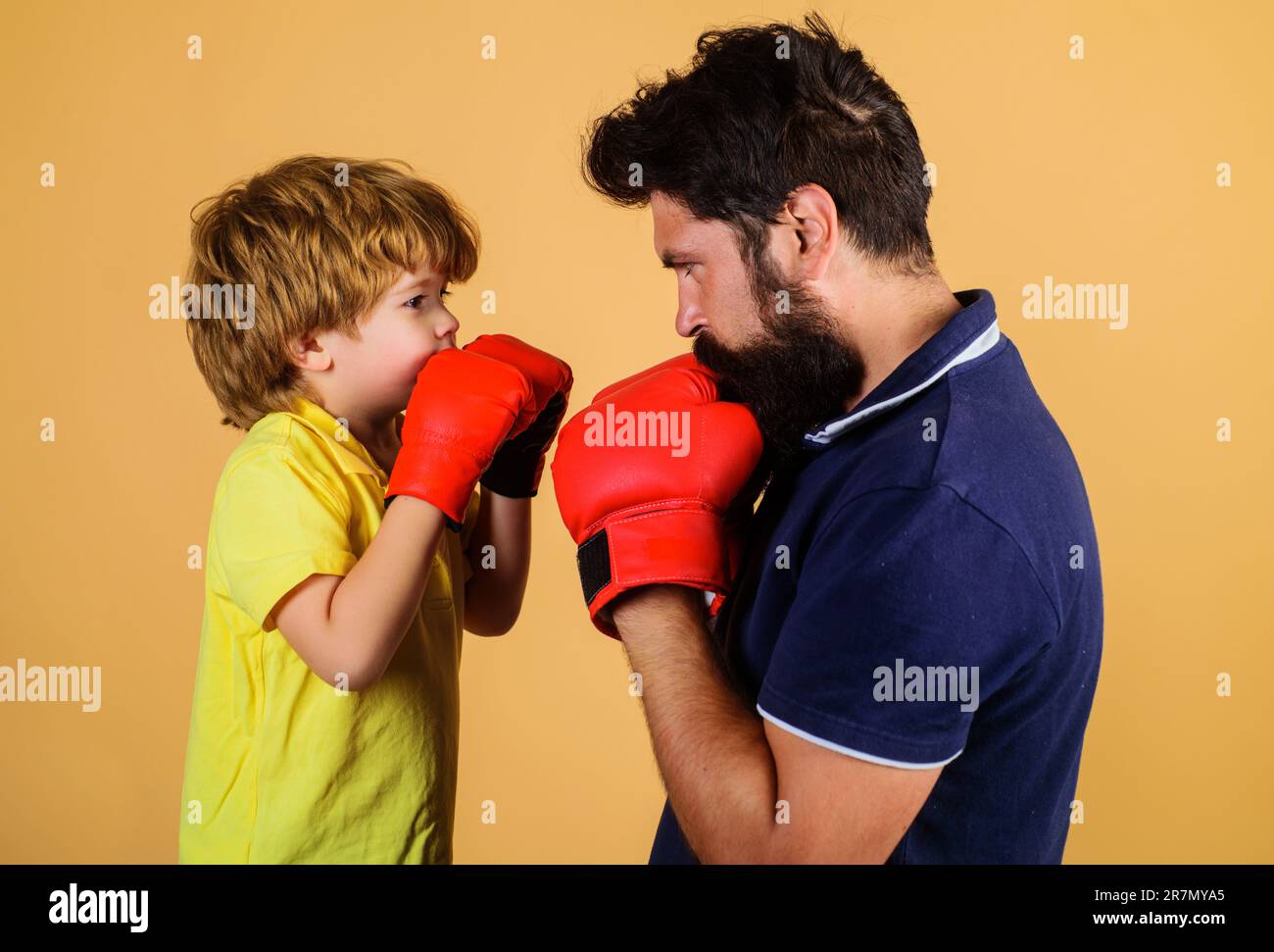 Kleiner Junge mit Boxtrainer. Boxerjunge übt Schläge mit Trainer. Vater und Sohn während des Boxtrainings. Ein Junge in Boxhandschuhen, mit dem er trainiert Stockfoto