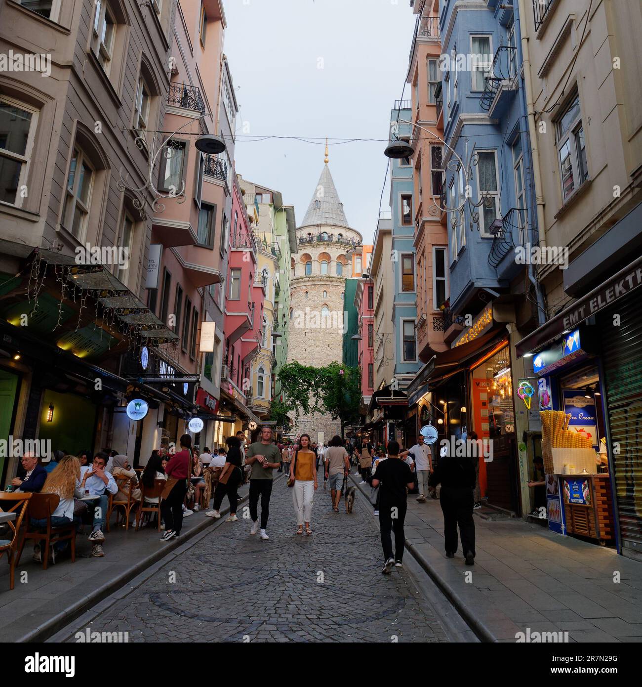 Touristen genießen eine malerische und geschäftige Straße bei Nacht mit dem Galatenturm dahinter, Istanbul, Türkei Stockfoto