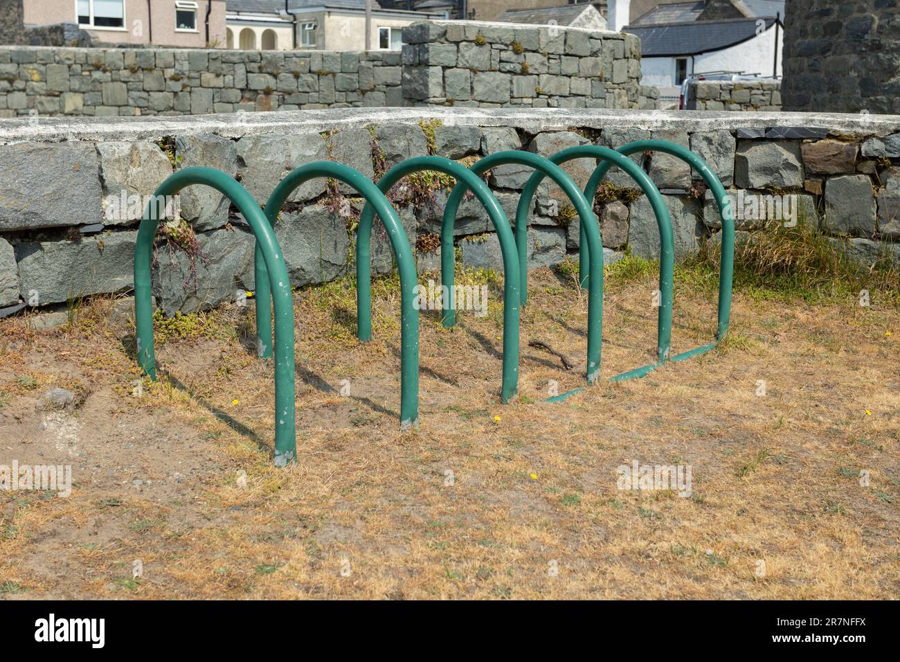 Fahrradständer aus grünem Metall oder Ständer auf festem Untergrund neben Rasen Stockfoto