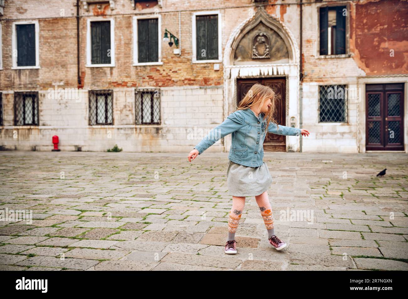 Außenporträt eines hübschen Mädchens, das durch die alten italienischen Straßen läuft, und ein Kind tanzt draußen. Stockfoto
