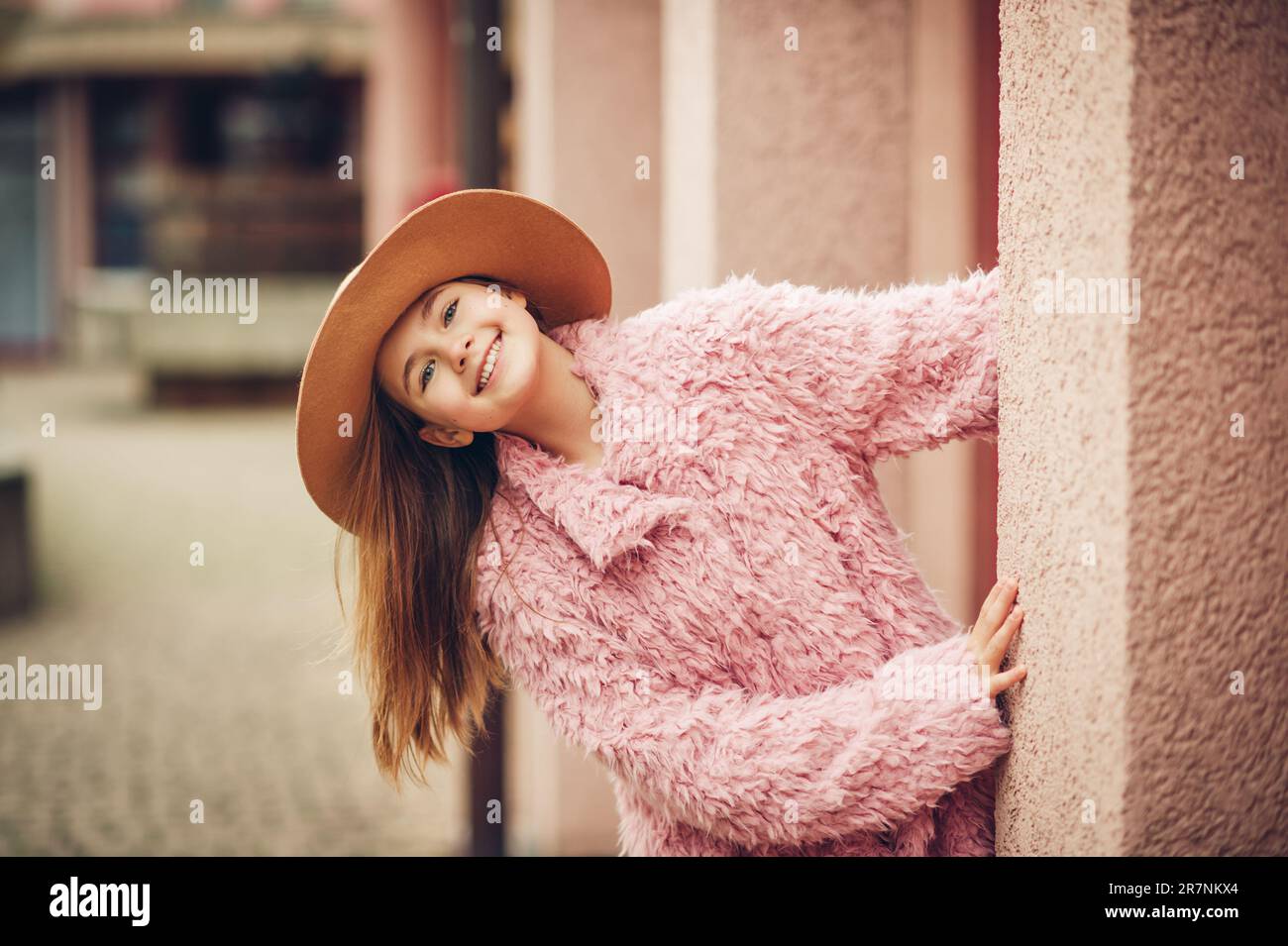 Outdoor-Modeporträt eines jungen Mädchens mit pinkfarbenem Kunstpelzmantel im Street-Stil Stockfoto