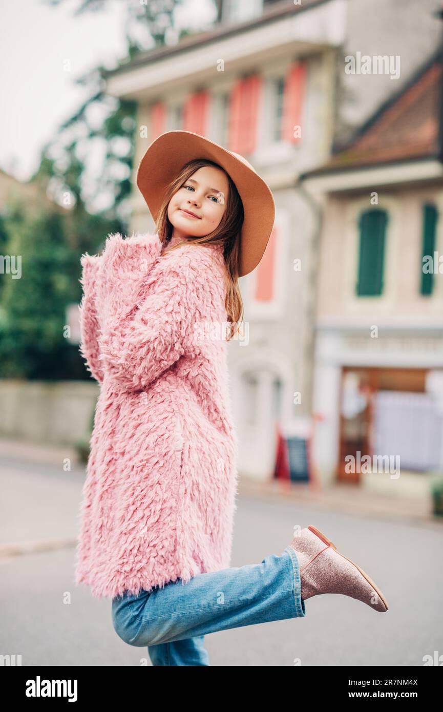 Outdoor-Modeporträt eines jungen Mädchens mit pinkfarbenem Kunstpelzmantel im Street-Stil Stockfoto