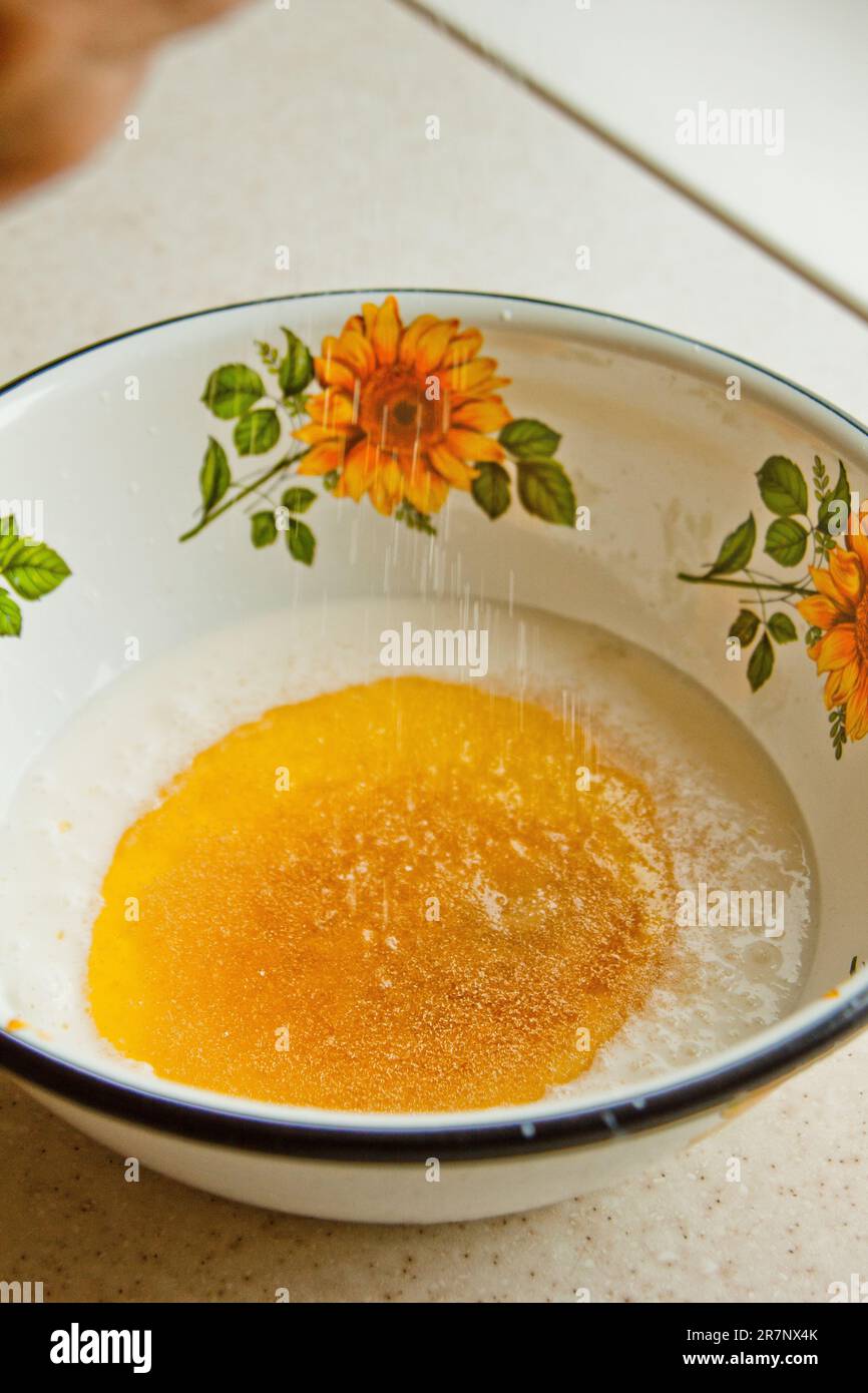 Öl, das in eine Metallschüssel in die Milch gegossen wird. Teigzubereitung. Rezeptpuffer-Gebäck. Backzutaten, Nahaufnahme, Draufsicht. Stockfoto