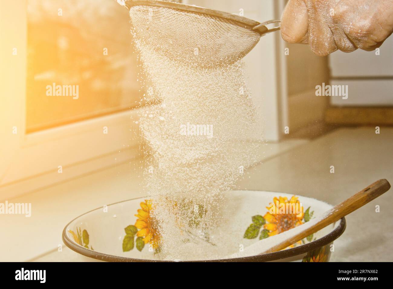 Weibliches Mehl, das von Hand durch ein manuelles Mehlsieb in einer Schüssel gesiebt wird, Nahkopie. Ich koche Teig. Küchengerät aus Metall. Stockfoto