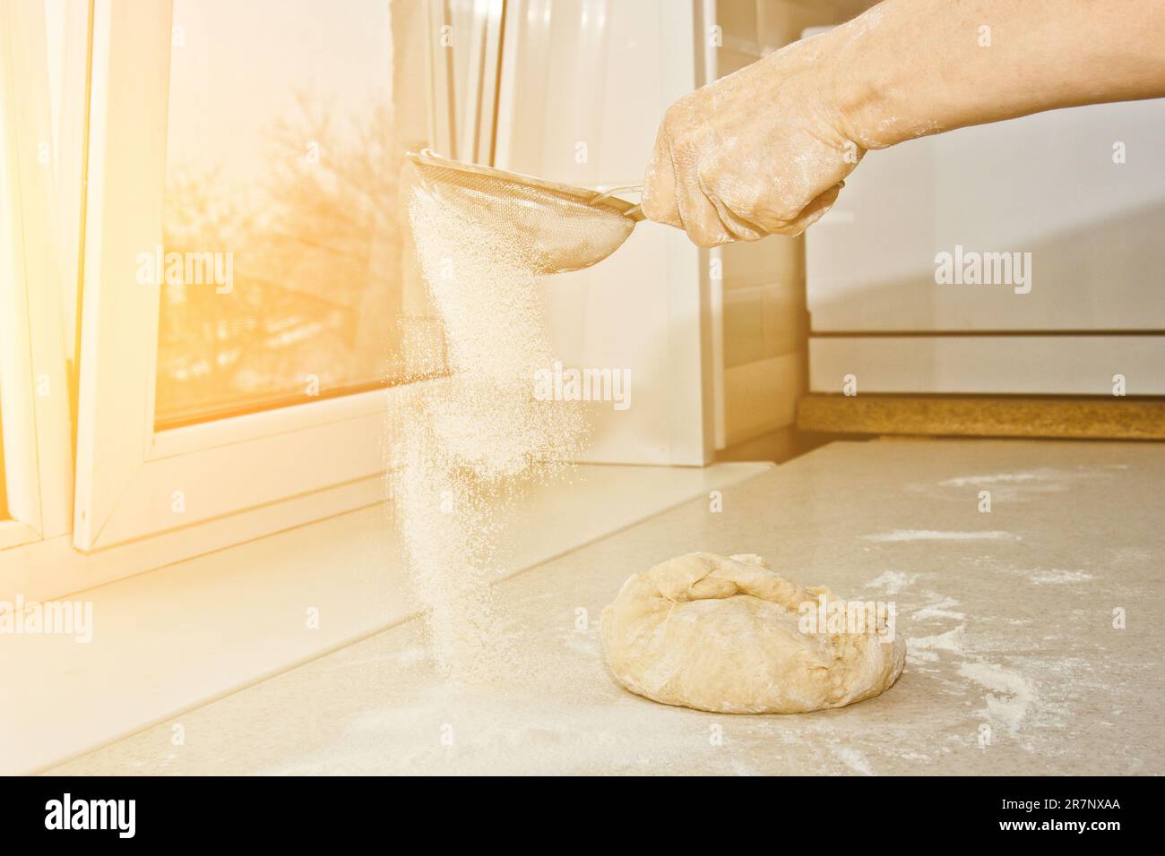 Weibliches Mehl, das von Hand durch ein manuelles Mehlsieb in einer Schüssel gesiebt wird, Nahkopie. Ich koche Teig. Küchengerät aus Metall. Stockfoto