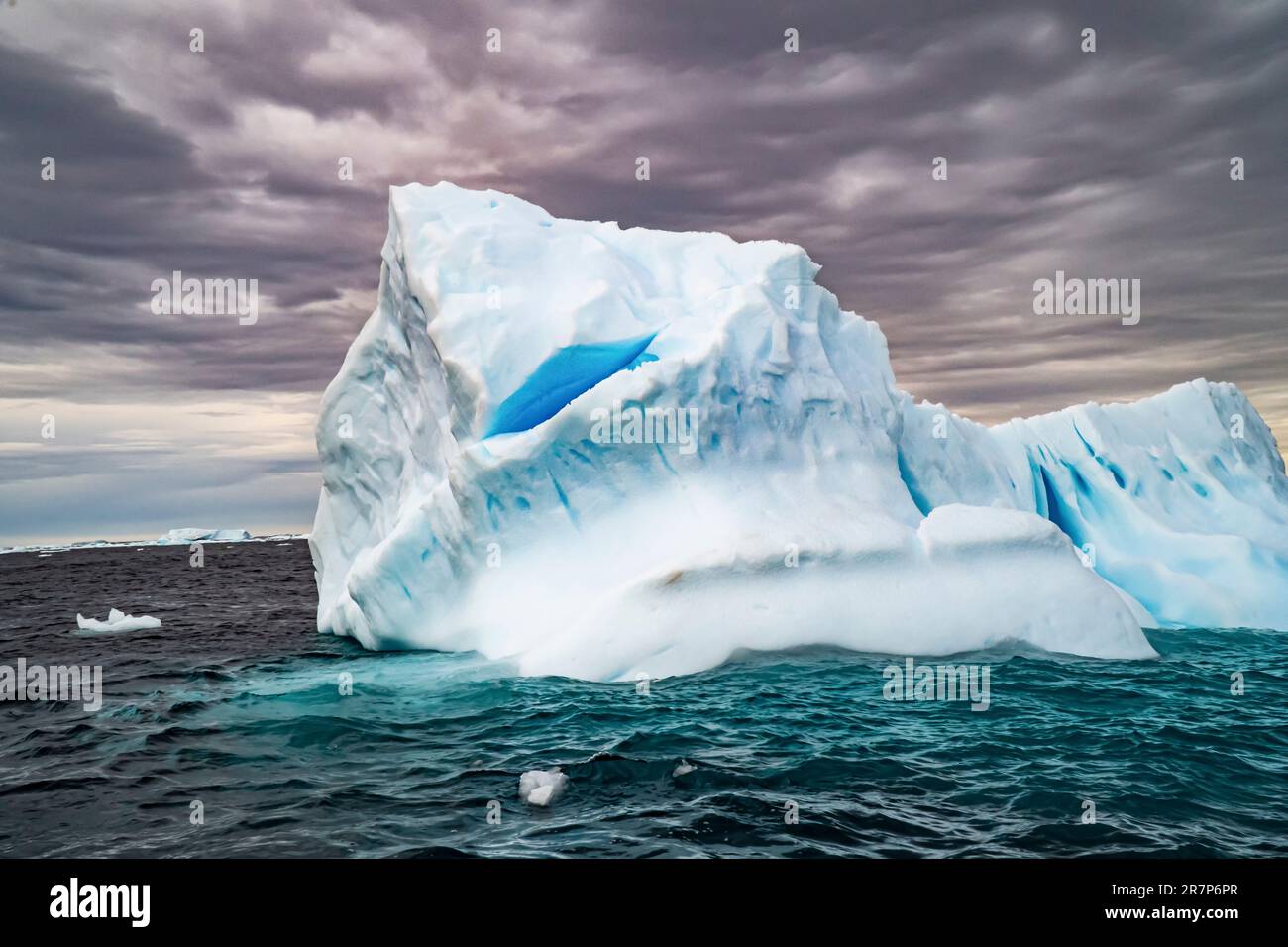 Schmelzender Eisberg mit Eisscholle im Vordergrund. Fotografiert in der Antarktis. Stockfoto