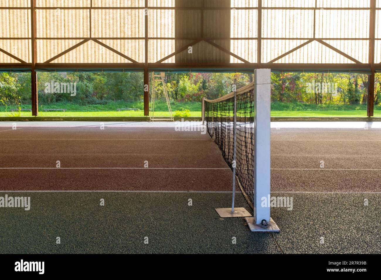 Heruntergekommener Tennishalle ohne Leute, die auf einem sonnenbeleuchteten Holzrand einen Blick haben Stockfoto