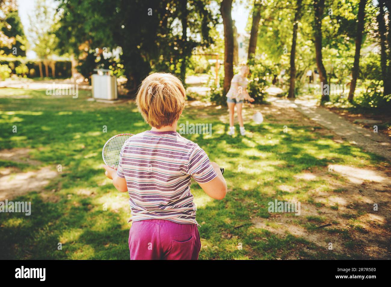 Gruppe von 2 lustigen Kindern, die Badminton im Sommerpark spielen. Kinder haben Spaß zusammen an einem schönen, sonnigen Tag Stockfoto