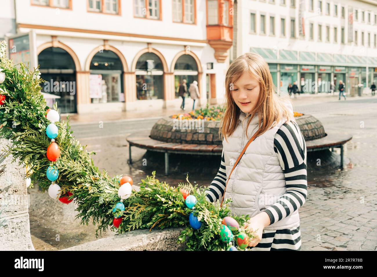 Außenporträt eines jungen Mädchens, das mit osterdekoration auf den Straßen der alten europäischen Stadt spielt Stockfoto