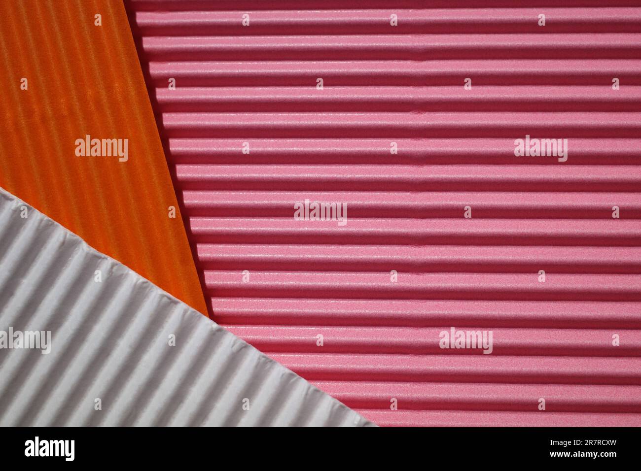 Horizontal und diagonal gerippter Karton mit den Farben Pink, Weiß, Orange. Als Hintergrund gemeint Stockfoto