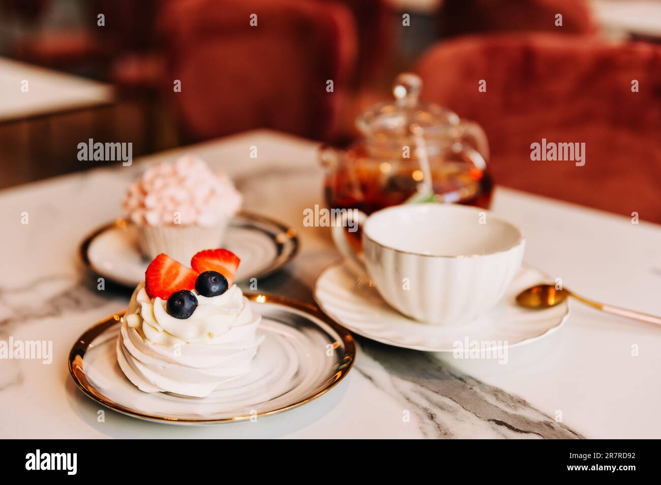 Tee mit Dessert, serviert am Tisch in einem gemütlichen Teeraum Stockfoto