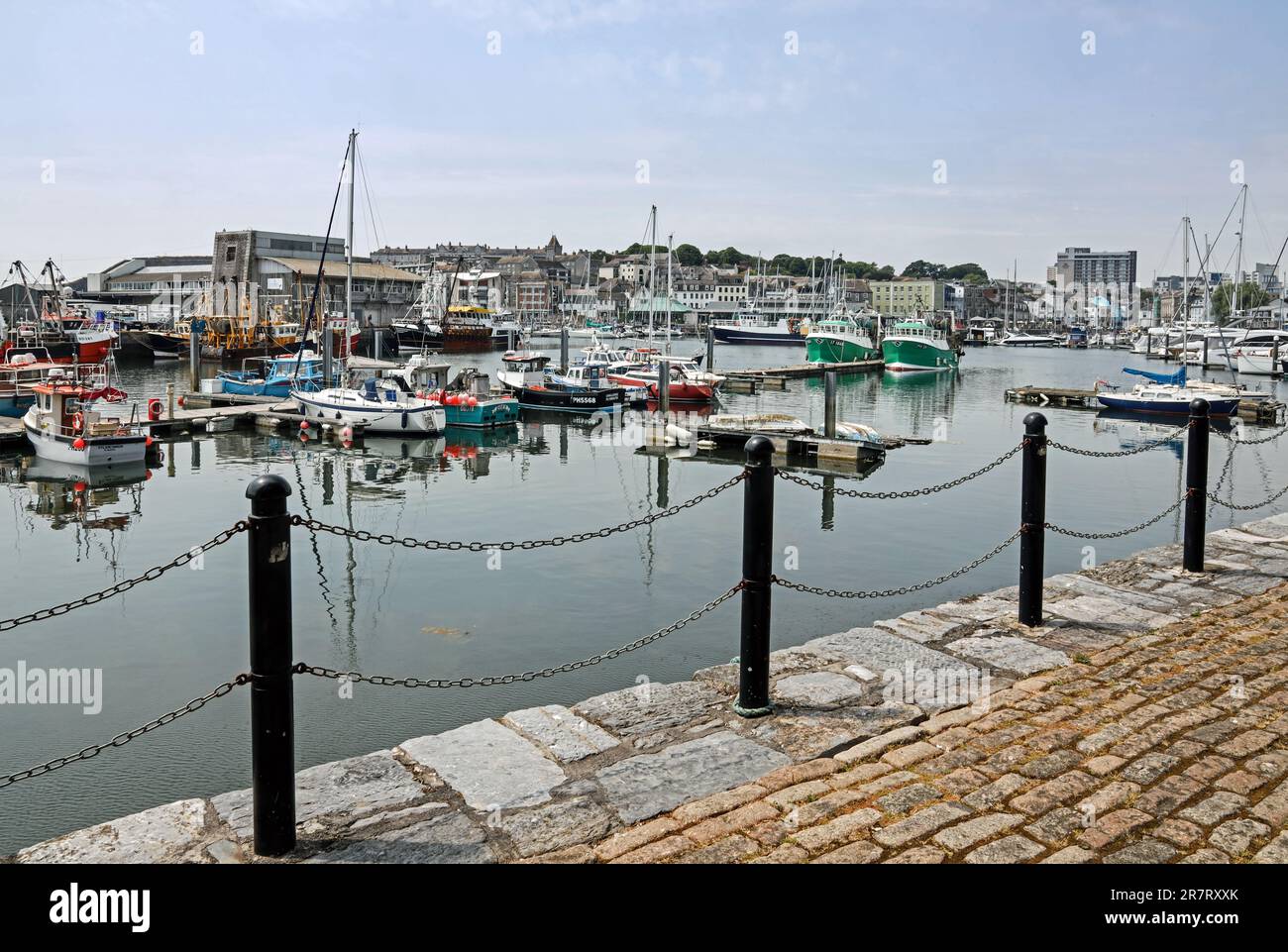 Plymouth Sutton Harbour, der Fischmarkt mit Fischerbooten und kleineren Booten im Vordergrund, in der Ferne der Barbican und zur vorderen Kai-Kette Stockfoto