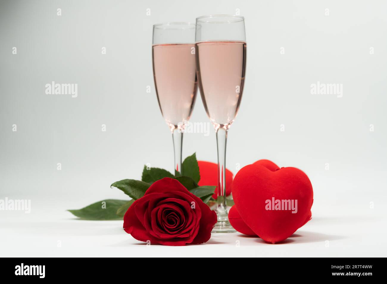 Champagnergläser, eine Rose und Herzen valentinstag mit weißem Hintergrund und Kopierraum Stockfoto