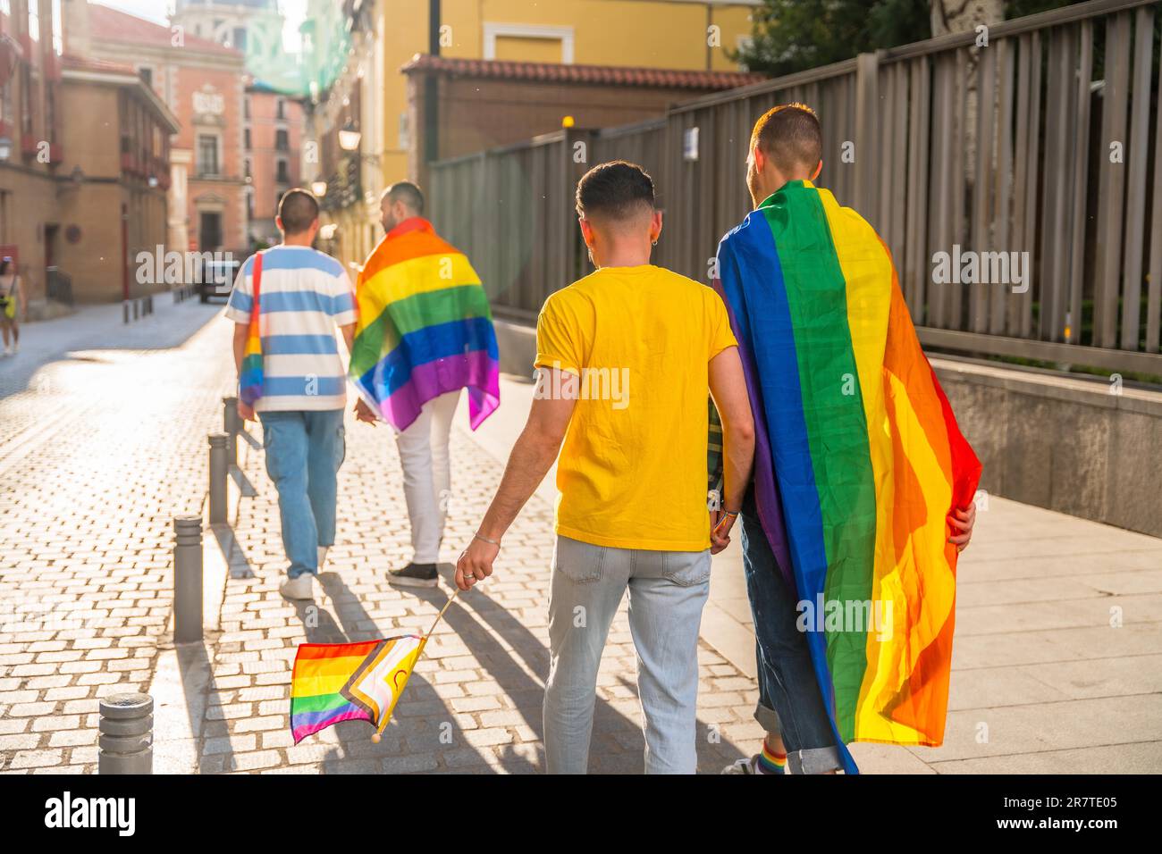 Schwulenstolz-Party in der Stadt, Männer mit dem Rücken zur Demonstration mit den Regenbogenflaggen, lgbt Concept Stockfoto