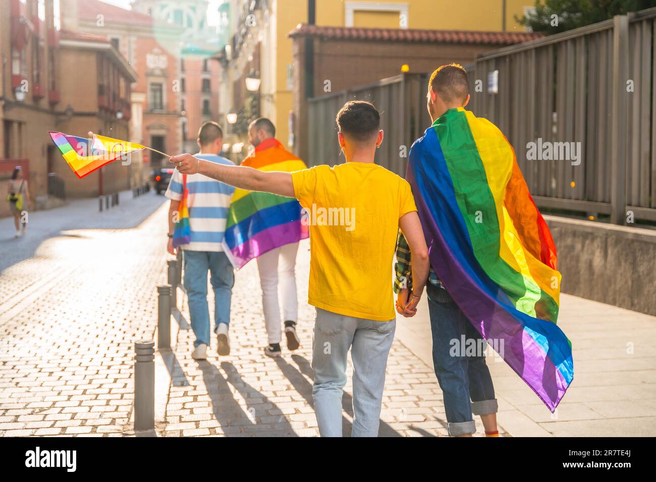 Schwulenstolz-Party in der Stadt, Männer mit dem Rücken zur Demonstration mit den Regenbogenflaggen, lgbt Concept Stockfoto