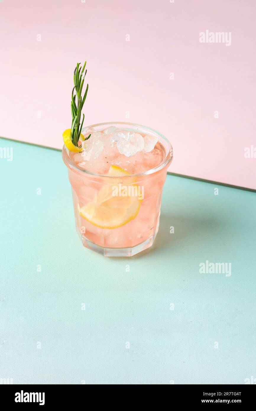 Pink Gin Cocktail mit Rosmarin auf pastellfarbenem Hintergrund Stockfoto