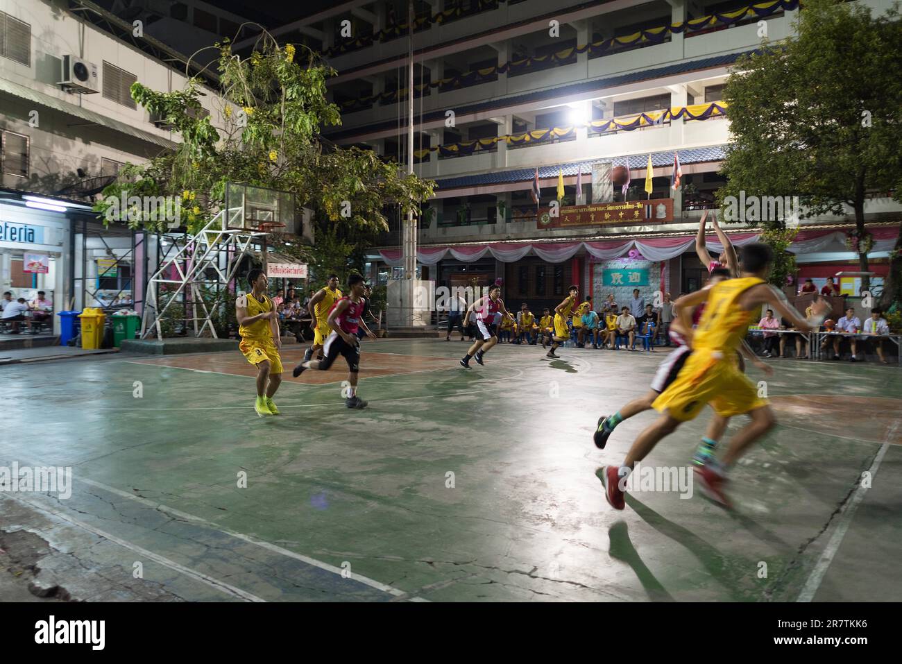 Kurze Pause bei einem nächtlichen Basketballspiel auf einem Sportplatz im Hinterhof einer Schule in Bangkoks Chinatown Stockfoto