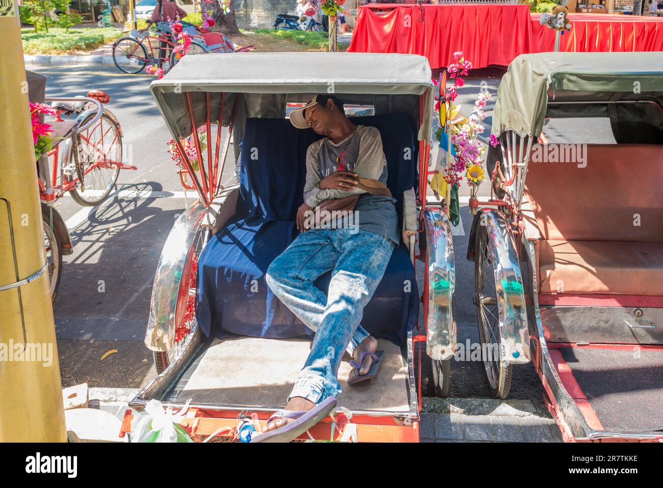 Der Fahrer schlief am frühen Nachmittag in seiner Rikscha in der Altstadt von Penang tief ein Stockfoto