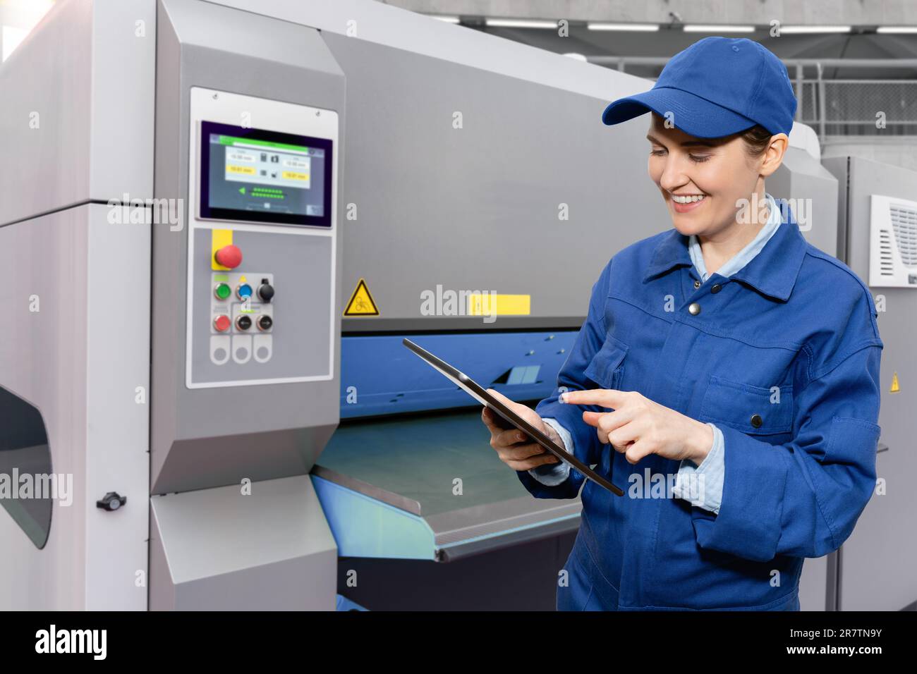 Frau mit digitalem Tablet steuert automatische Werkzeugmaschinen in einer intelligenten Fabrik. Stockfoto