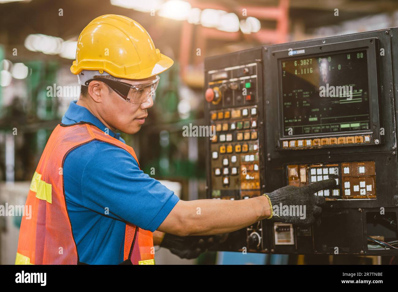 Asiatischer Industriebetrieb, der eine CNC-Maschine zum Fräsen von Drehmaschinen bei der Metallbearbeitung in der Schwerindustrie bedient. Stockfoto