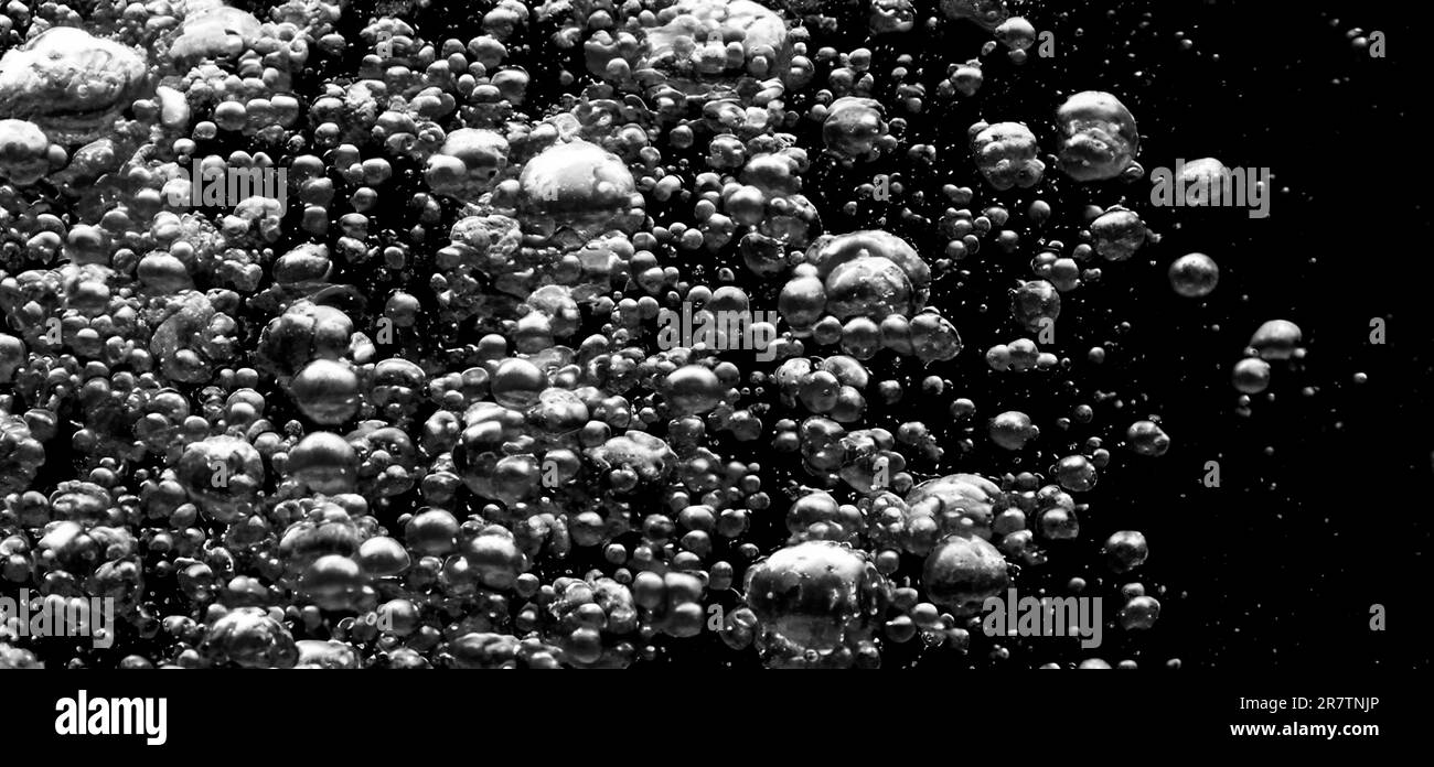 Soda-Wasserblasen, die unter Wasser vor schwarzem Hintergrund spritzen. Flüssige Cola-Textur, die wie eine Explosion in Ununde an die Oberfläche schwebt Stockfoto