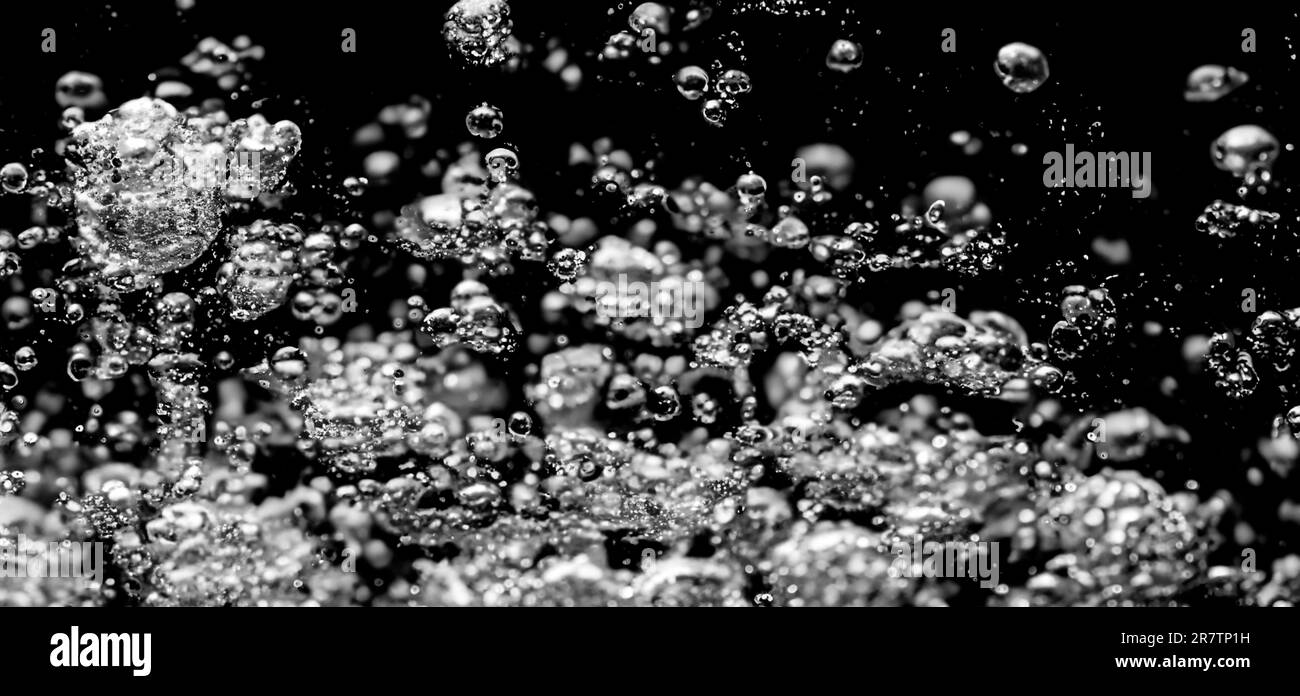 Soda-Wasserblasen, die unter Wasser vor schwarzem Hintergrund spritzen. Flüssige Cola-Textur, die wie eine Explosion in Ununde an die Oberfläche schwebt Stockfoto