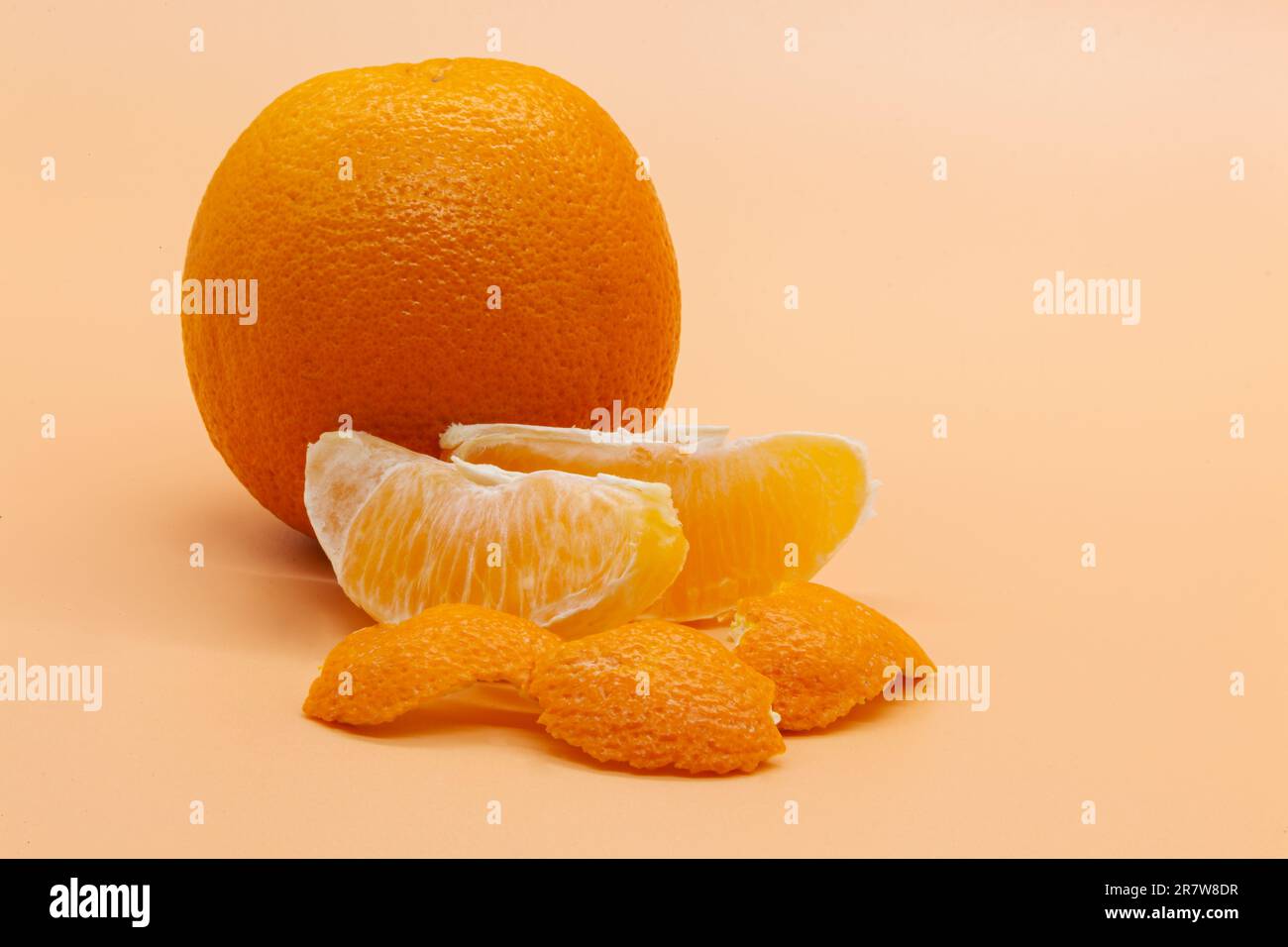 Ganze orangefarbene und orangefarbene Scheiben mit Schale auf orangefarbenem Hintergrund. Motivfoto. Hochwertiges Foto. Horizontal Stockfoto